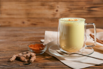 Cup of healthy turmeric latte on wooden table