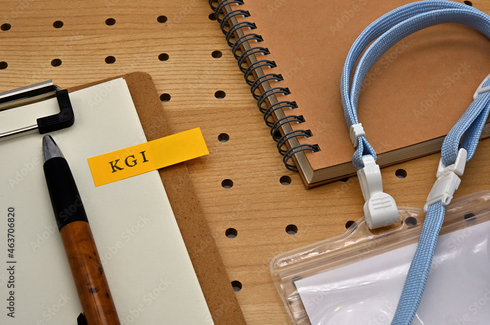 Poster there is a sticky note with the letters kgi stamped on the edge of a clipboard placed along with a n