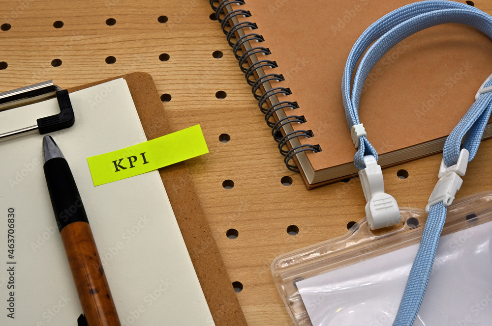 Poster there is a sticky note with the letters kpi stamped on the edge of a clipboard placed along with a n