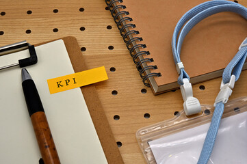 There is a sticky note with the letters KPI stamped on the edge of a clipboard placed along with a...