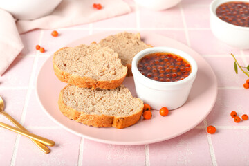 Plate with fresh bread and rowan berry jam on table