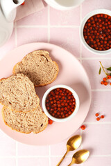 Plate with fresh bread and rowan berry jam on table