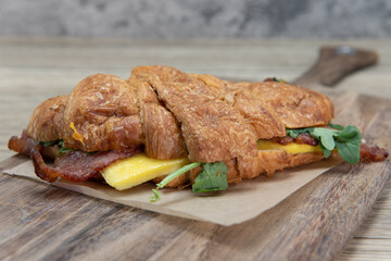 Bacon and eggs served inside a breakfast croissant roll for a sandwich on the go to eat