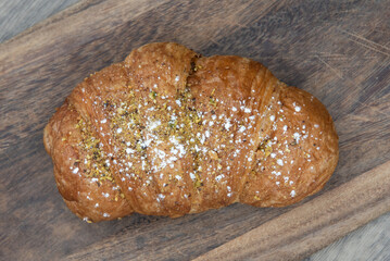 Overhead view of pistachio nutella breakfast croissant served fresh from the oven on a wooden platter