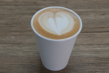 Warm cup of latte with a heart pattern floating in the foam on the surface