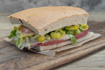 Enormous breakfast sandwich stacked tall with meat, lettuce, vegetables, and melted cheese for a hearty start of the day