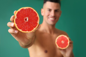 Naked young man with grapefruit on color background. Vegan Day