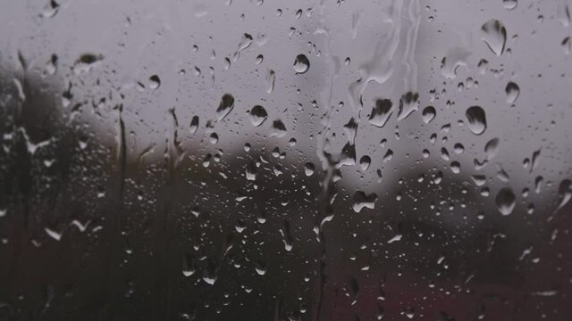strong rain water droplets stream dowm on window glass in downpour bad autumn weather