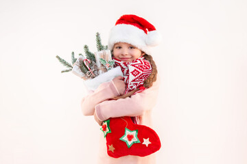 A little girl in a beautiful outfit for the new year holds a lot of gifts and jewelry in her hands. A girl on an isolated background.