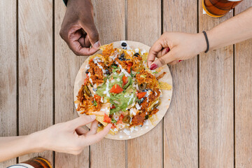 Crop friends dipping nachos in guacamole