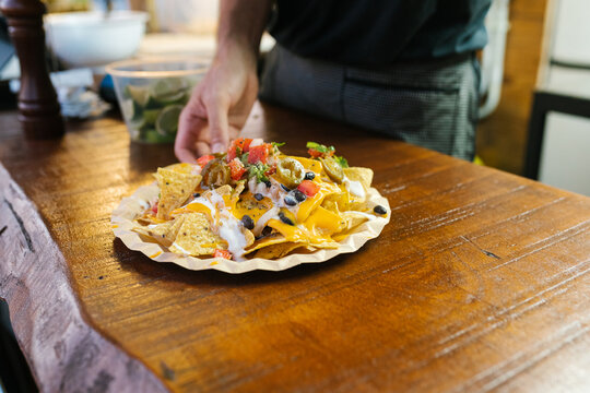 Anonymous cook placing a plate of mexican nachos