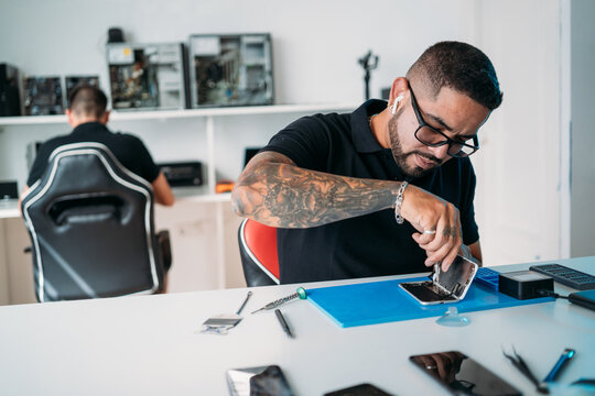 Worker with screwdriver repairing smartphone