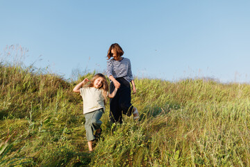 Happy girl with mother waling down the hill 