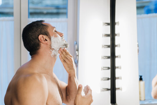 Man smearing foam ob beard