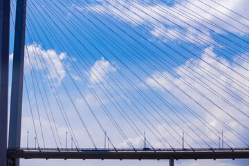 Fototapeta premium Vladivostok, 2017 - The Golden Bridge over the Golden Horn Bay in Vladivostok. Cars drive along the roadway of the suspension bridge against the background of the sea.