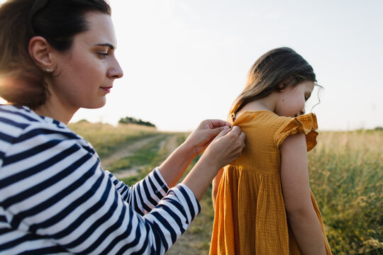 Mother buttoning up her daughter 