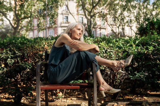 Grey-haired woman sitting with legs hanging