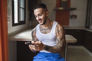 Horizontal closeup of a handsome tattooed guy smiling at his phone
