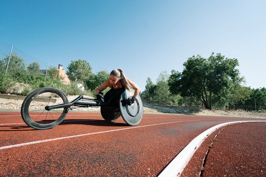 Female wheelchair athlete adjusting her chair on sports track