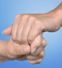 Hands of caregivers and the elderly human on a background