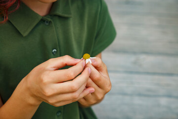 Crop child picking flower petals