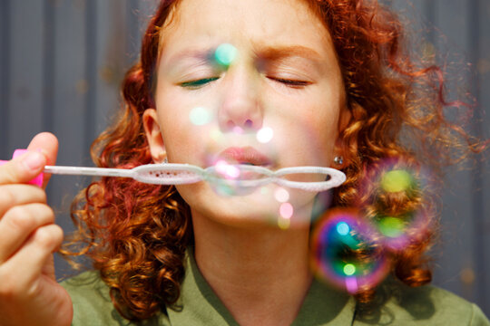 Redhead girl blowing iridescent bubbles