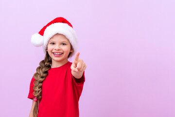 A girl in a New Year's hat points her finger forward.