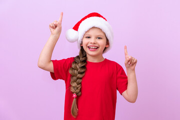 A child in a Christmas hat is very happy and points his fingers up.