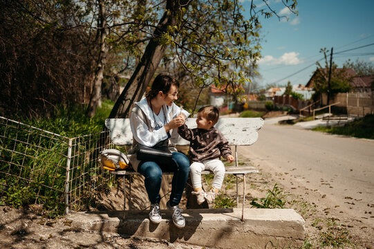 Son Giving Flower To Mom On Bench.