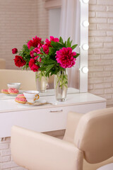 Client place in hairdressing beauty salon with cup of tea, donuts and peonies flowers