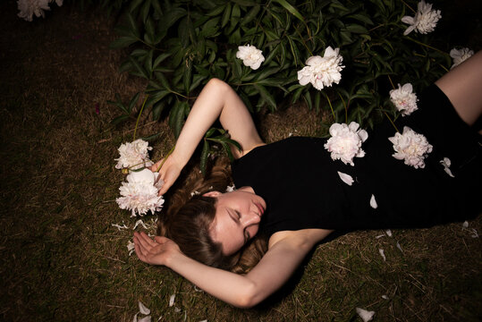 Woman lying among white peonies