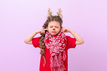 A little girl in a Christmas reindeer outfit and with a warm scarf put her fingers in her ears and closed her eyes.
