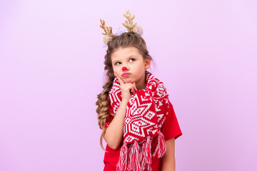A little girl in a Christmas reindeer outfit holds her hand near her cheek and looks away very thoughtfully.