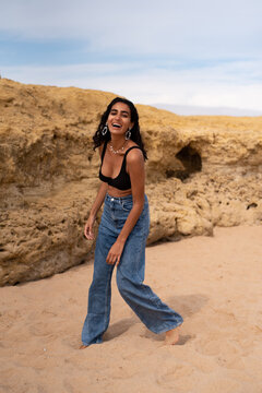 Woman in bikini top and jeans playing on the beach