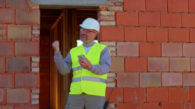 Civil engineer architect specialist throwing money dollars cash, celebrating success at construction site. Developer builder in helmet scatter the dollars, spending money. Real estate building house