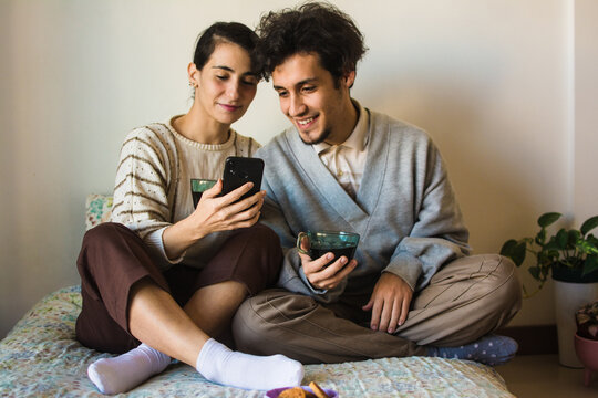 Couple smiling while watching videos on a cell phone