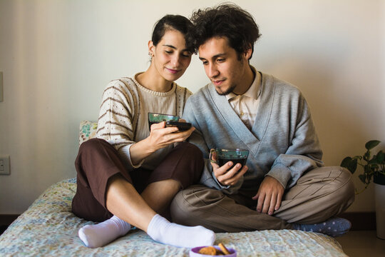 Couple in bed watching videos in a phone together