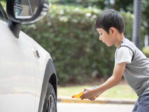 Chinese boy washing a car with a toy gun