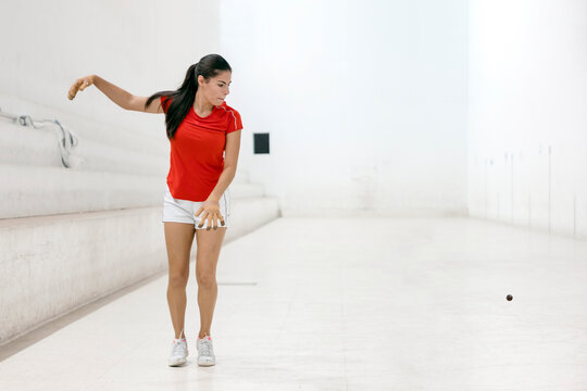 Female player playing traditional spanish game "Valencian Pelota" raising her arm to reach the ball in court