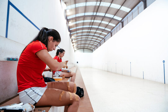 Side view of athlete woman protecting her hands with tapes that have previously supported on the leg to play traditional spanish game