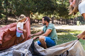 Parents setting up tent with daughter