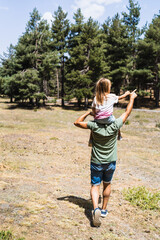 Father with daughter walking towards forest