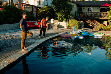 Moms watch girl in pool with inflatable toys