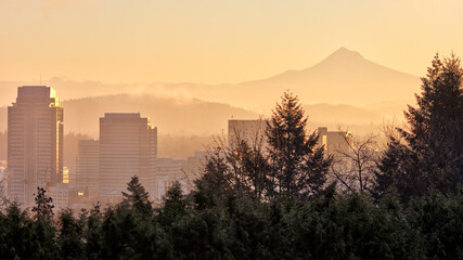 Fogyy golden sunrise over Portland, Oregon skyline with Washington Park in foreground and Mt. Hood in the distance