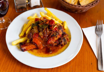 Plate with appetizing juicy pork knuckle with stewed vegetables and delicious French fries