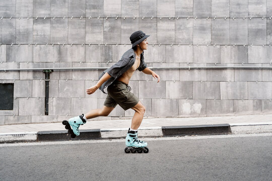 Side view of a young man roller skating on the street in the city