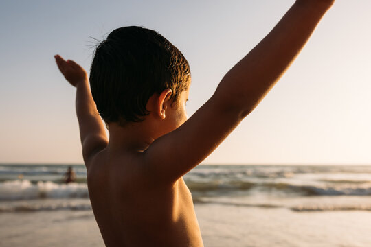 Carefree boy on beach at sunset