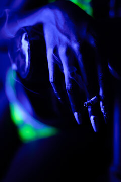 woman holds cigarette in her hand with a blue light effect