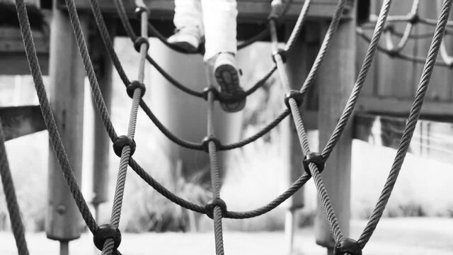 Lonely girl in pajamas climbing a rope playing alone no friends to play with in the playground A child left by his parents to play alone, lonely, wants to play with his friends.