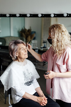 Makeup artist applying make up to senior woman